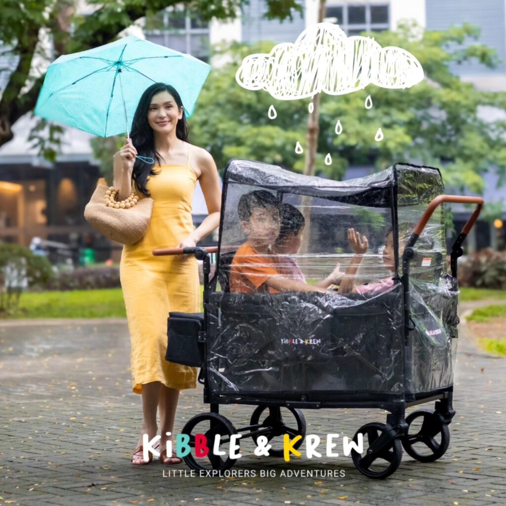 Lady in yellow dress holding an umbrella with her kids on a stroller wagon by kibble and krew